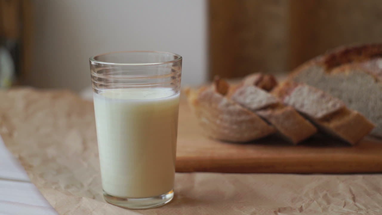 стакан молока и кусочки хлеба на кухонном столе. стакан молока и кусочки хлеба