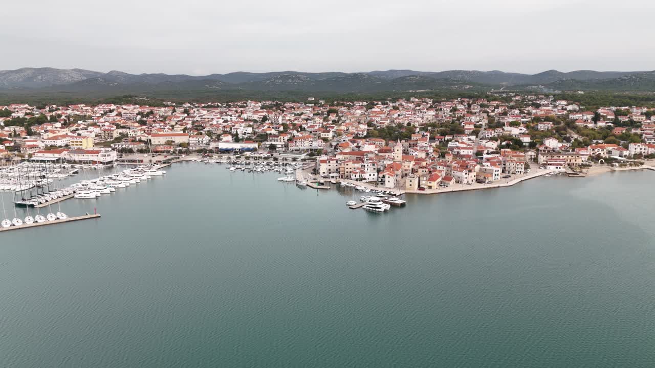 Mare Adriatico calmo, ripresa aerea da drone dell'ampia costa di Pirovac con porto turistico, Croazia