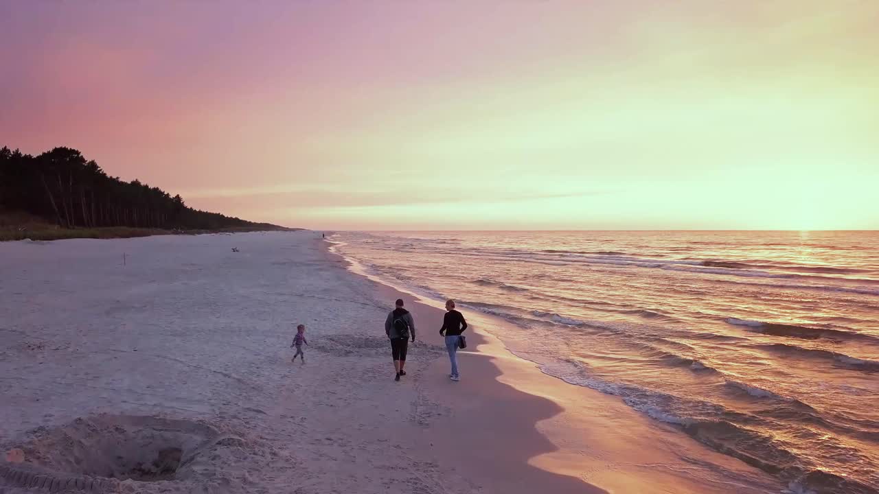 해가 지면 해변에서 산책하는 가족