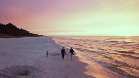 family walking on the beach at sunset