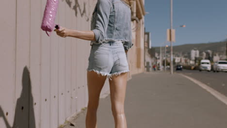 sexy-woman-painting-wall-with-pink-paint-walking-in-city-street-confident-female-artist-enjoying-creative-expression-with-urban-graffiti-art-with-rgb-glitch