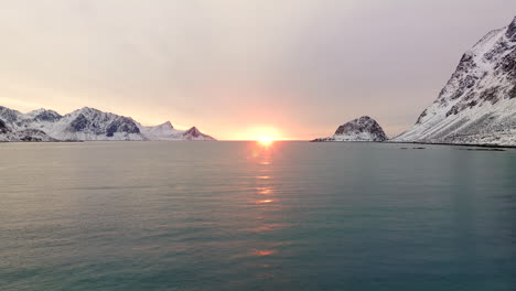 poner el sol en el horizonte sobre el fiordo de haukland superficie de agua de las islas lofoten en la temporada de hielo, noruega