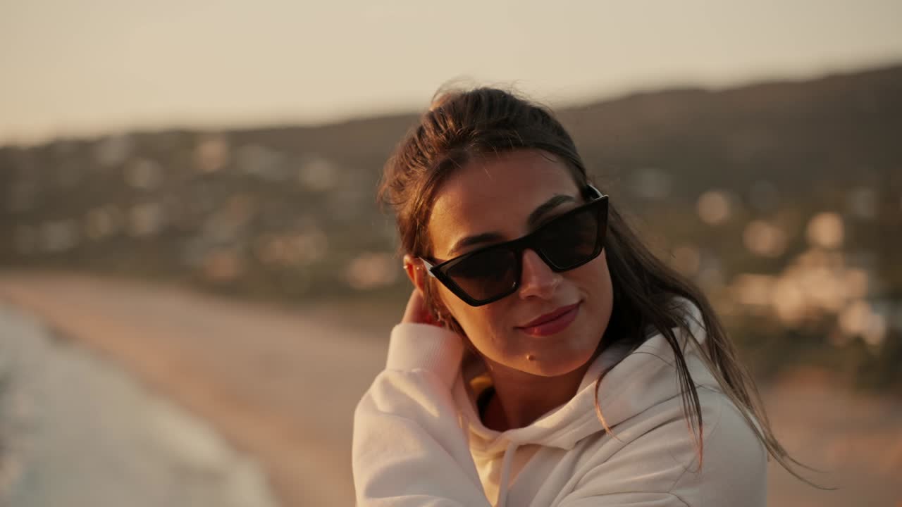 Slowmotion bokeh-opname van een aantrekkelijke vrouw aan de kust tijdens zonsondergang.