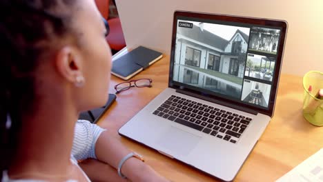 African-american-woman-watching-home-cctv-camera-views-on-laptop,-slow-motion