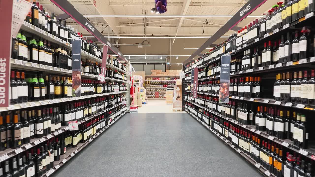 Una lenta carrellata in avanti si muove attraverso lunghi corridoi di bottiglie di vino a Libourne