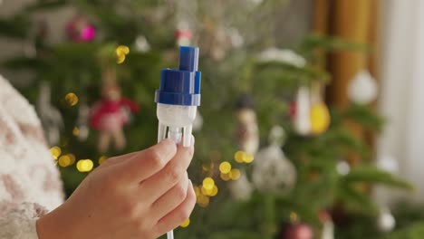 a young girl holds a nebulizer next to the christmas tree - close up