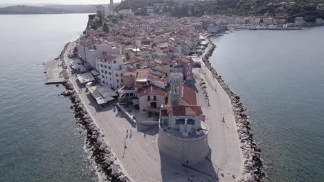 video with a bird's eye view of the lighthouse of the city of piran in slovenia, with people walking and the church in the background