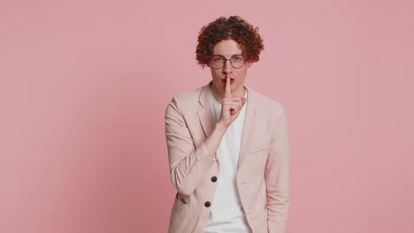 jonge man drukt vinger op lippen maak stilte gebaar teken vertel geen geheim stop roddelen privacy