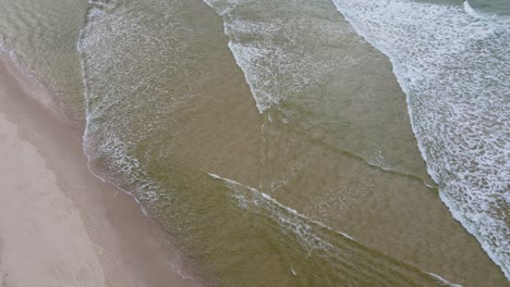 olas de agua blanca rodando suavemente hacia las arenas perfectas de la playa kingscliff en nueva gales del sur, australia - toma aérea de arriba hacia abajo
