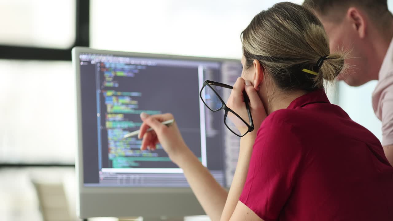 Two people collaborating while looking at code on a computer screen