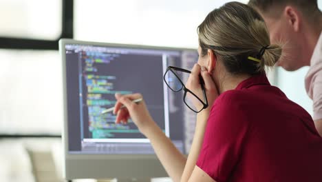 two people collaborating while looking at code on a computer screen