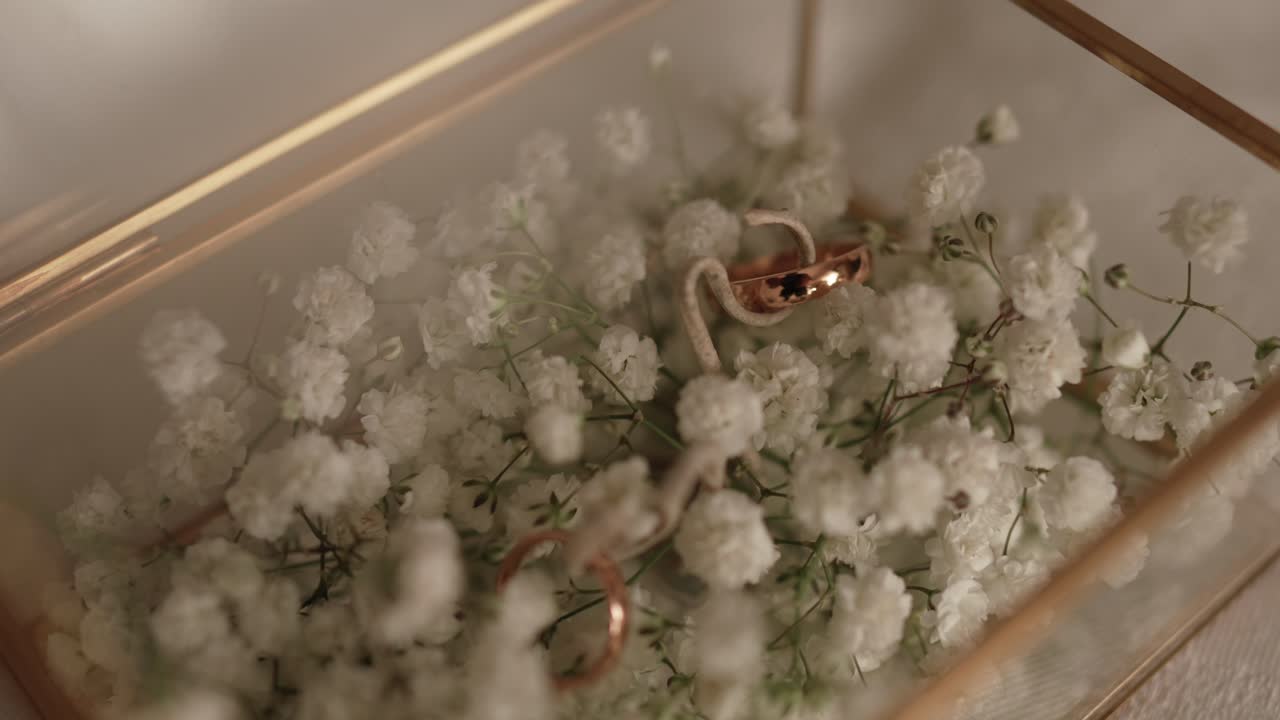 gold rings in floral filled box with delicate baby’s breath flowers