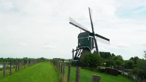 4k-Molino-De-Viento-Oukoopse-Molen-De-Pie-En-La-Típica-Naturaleza-Holandesa-Con-Tierras-Verdes,-Líneas-De-Liderazgo-De-La-Cultura-Holandesa