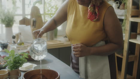 african american woman adding water to bowl while cooking