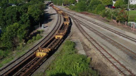 Aerial-view-of-rusty-train-cars-moving-through-a-curve-on-a-set-of-tracks-on-a-sunny-day-in-the-morning