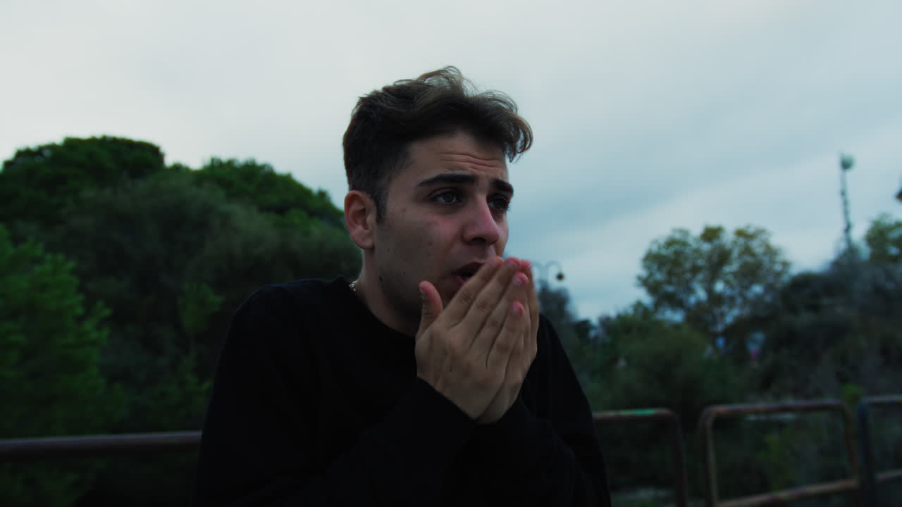 소년은 버스를 기다리고 우울한 구름이 가득한 겨울에 추워집니다.