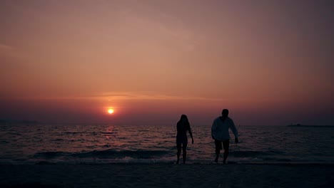 Silhouetten-Junger-Menschen,-Die-In-Zeitlupe-Am-Meer-Entlang-Spazieren