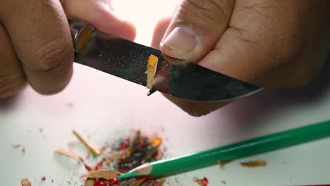 Footage-of-hands-slowly-sharpening-a-pencil-and-some-coloured-pencils-with-a-sharp-knife