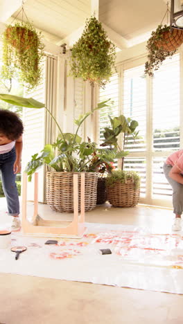 vertical video: painting on canvas, two women enjoying creative activity in bright room