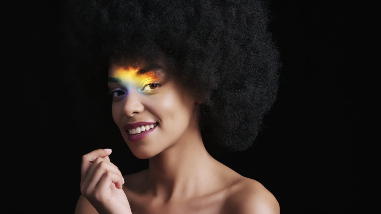 retrato multicolor de cerca hermosa mujer afroamericana con afro disfrutando de una piel suave y saludable con aspecto confiado belleza natural luz colorida sobre fondo negro concepto de cuidado de la piel