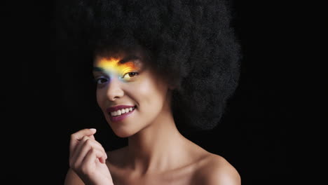 retrato multicolor de cerca hermosa mujer afroamericana con afro disfrutando de una piel suave y saludable con aspecto confiado belleza natural luz colorida sobre fondo negro concepto de cuidado de la piel