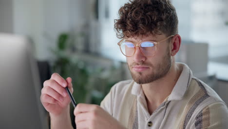 man with curly hair and glasses holding a pen