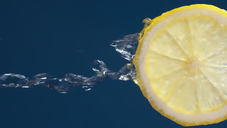 vertical of slow motion macro shot of flowing water from lemon slice on blue-black background