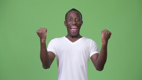 young african man looking excited against green background