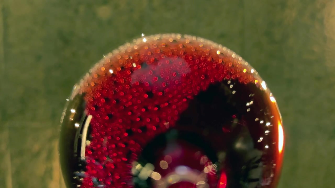 Vista artistica di vino rosso che si versa in un bicchiere dal basso.