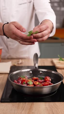 chef preparing a dish with tomatoes, onions and coriander