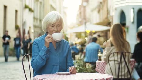 Alte-Schöne-Großmutter-Mit-Grauem-Haar-Trinkt-Kaffee-Und-Ruht-Sich-Im-Café-Im-Freien-Aus