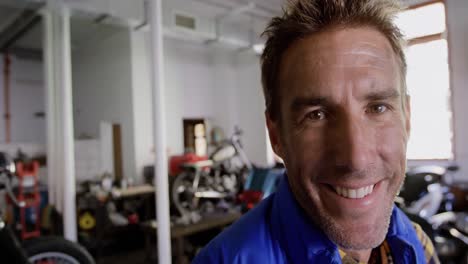 mecánico masculino mirando a la cámara en el garaje de reparación de motocicletas 4k