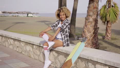 happy young female skateboarder sitting cheering