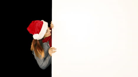 Beauty-brunette-in-santa-hat-pointing-white-poster