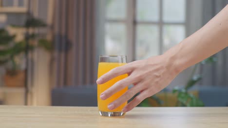 man hand take glass of orange juice on table