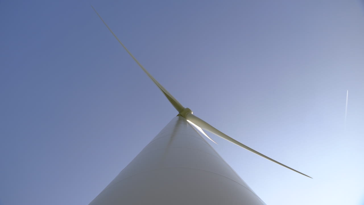 Looking up along the shaft of a spinning wind turbine