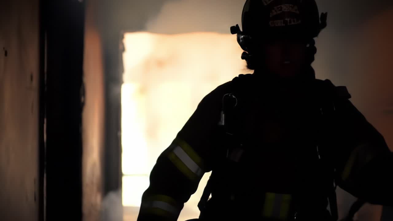 A firefighter steps out of a smoke-filled structure while battling a blaze during a rescue operation at night. The team works to ensure safety and control the situation.