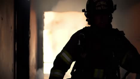 a firefighter steps out of a smoke-filled structure while battling a blaze during a rescue operation at night. the team works to ensure safety and control the situation.