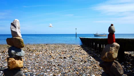 colourful rocks arrangement balanced on sunny llandudno beach seaside shoreline with boat between