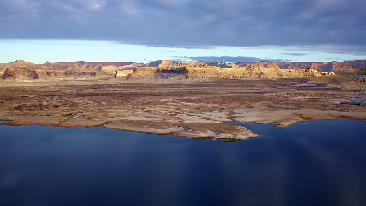 Drone shot flying smoothly over lake powell towards interesting rock formations of Glen Canyon