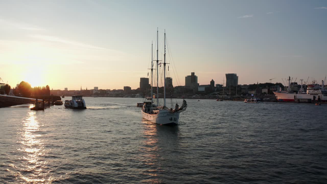 velero en el puerto de hamburgo navegando durante la hora dorada junto a la filarmónica del elba y el rey león