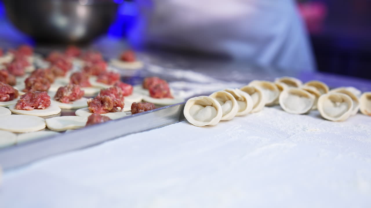 Meat dumplings manufacturing at modern food factory. Workers lay the ready-made ravioli on a tray. Close up.