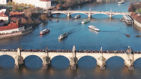 aerial view of charles bridge over river and multiple tourist boats float