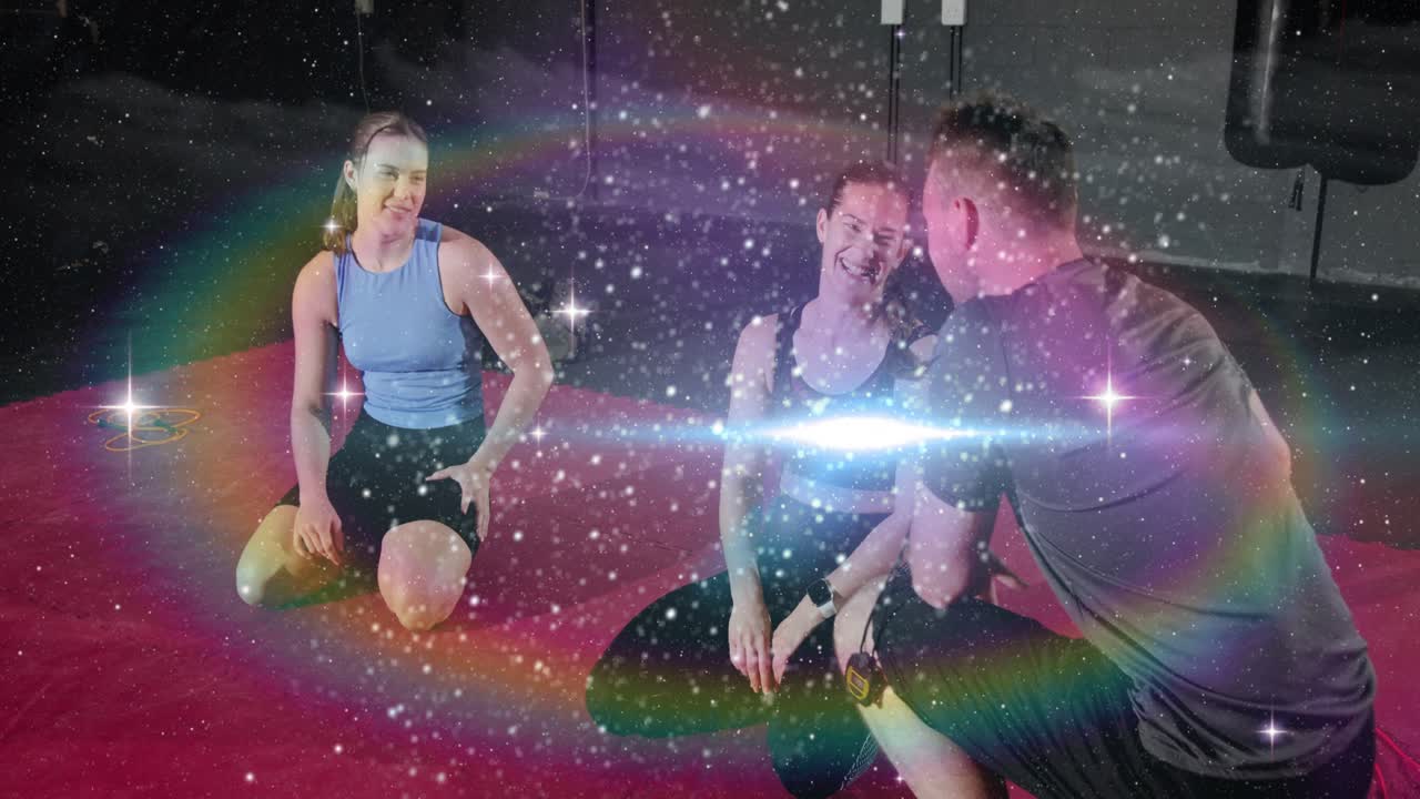 Fitness coach entering, kneeling by two trainees on pink mat, timing with stopwatch under sparkles