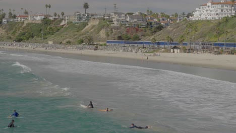 Amtrak-Zug-Bewegt-Sich-Durch-San-Clemente,-Während-Surfer-In-Den-Wellen-Spielen