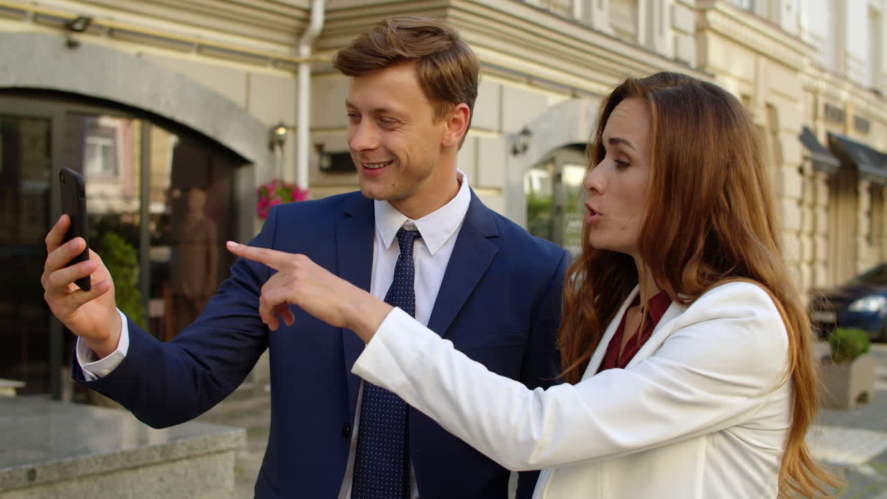 pareja de negocios confiada teniendo una videoconferencia en el teléfono móvil al aire libre