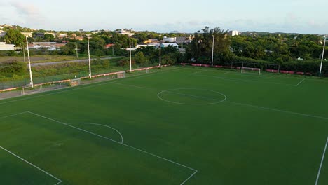 Beautiful-green-soccer-field-in-center-of-outdoor-track-at-sunset