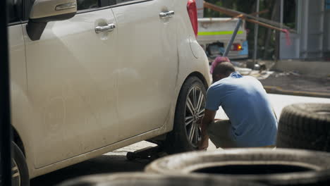 a man replaces a tire on a car in the dominican republic.