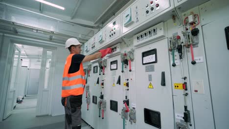 el ingeniero eléctrico que trabaja comprueba la tensión de corriente eléctrica y la sobrecarga en la parte delantera del gabinete del centro de carga o de la unidad de consumo para el mantenimiento en la sala principal del sistema de distribución de energía.