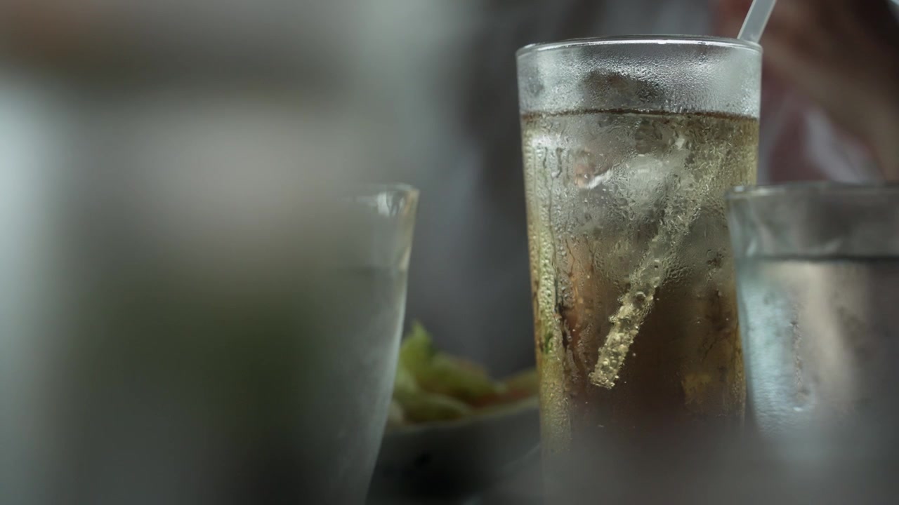 Primo piano di bevanda fredda con cubetti di ghiaccio e bollicine che salgono.